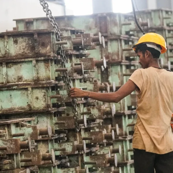 Worker operating industrial machinery at a ductile and grey iron casting foundry